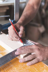 Junger männlicher Tischler, der mit Bleistift und Lineal in der Werkstatt auf Holz markiert - JAQF00226