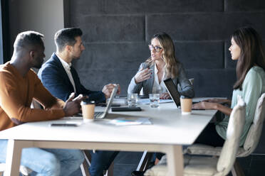 Business people having discussion in meeting while sitting at office - JSRF01331