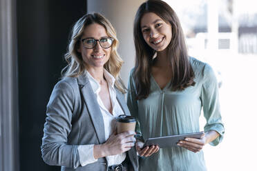 Businesswomen smiling while standing in office - JSRF01342