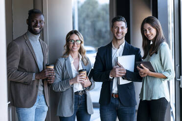 Confident business team smiling while standing together at office - JSRF01348