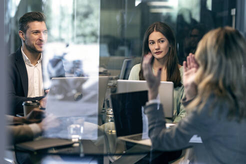 Businesswoman discussing with colleague while sitting in meeting at office - JSRF01360