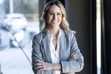 Confident businesswoman smiling while standing at office - JSRF01373