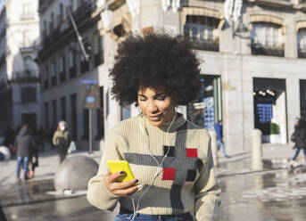 Smiling woman using mobile phone while standing in city - JCCMF01072