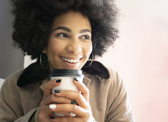 Smiling afro woman drinking coffee while sitting at cafe - JCCMF01106