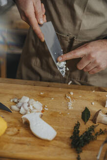 Expertise cutting onion and mushroom on cutting board while standing in kitchen - MFF06984