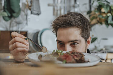 Koch konzentriert sich beim Garnieren eines Tomahawk-Steaks mit Gemüse in der Küche - MFF07067