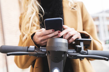 Frau mit Elektro-Scooter und Smartphone - FMOF01319