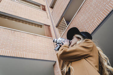 Blonde Frau filmt Gebäude durch eine alte Videokamera - FMOF01352