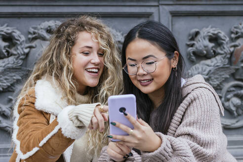 Multiethnische Freundinnen, die ihr Mobiltelefon gegen die Tür halten - JRVF00200