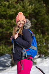 Lächelnde Frau mit Rucksack schaut im Winter weg - OCMF02032