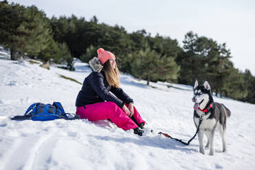 Mid adult woman with Siberian Husky on snow covered field during winter - OCMF02033