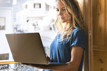 Konzentrierte Frau bei der Arbeit am Laptop zu Hause - SBOF02644