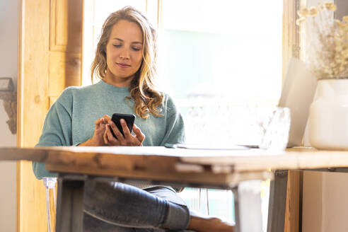 Eine Unternehmerin benutzt ihr Smartphone, während sie zu Hause sitzt - SBOF02653