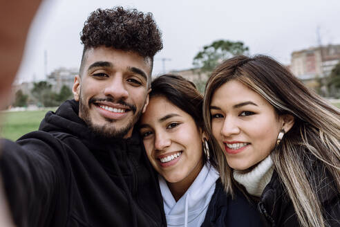 Young man with female friends taking selfie at park - XLGF01109