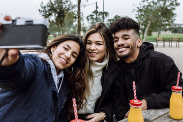 Lächelnde Freunde machen ein Selfie durch eine alte Kamera im Park - XLGF01113