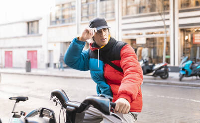 Asiatischer Mann mit Elektrofahrrad auf der Straße in der Stadt - JCCMF01116