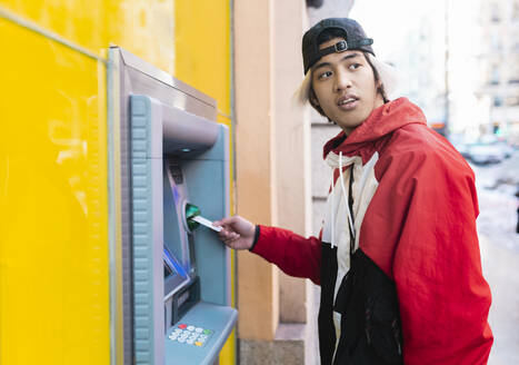 Asiatischer Mann, der Geld von einem Geldautomaten abhebt - JCCMF01127