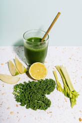 Healthy summer green juice with apple, lemon, kale and celery against wall - GEMF04631