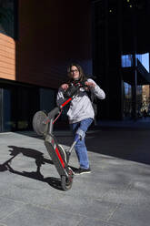 Behinderter junger Mann mit Elektro-Scooter auf dem Gehweg stehend - VEGF03758