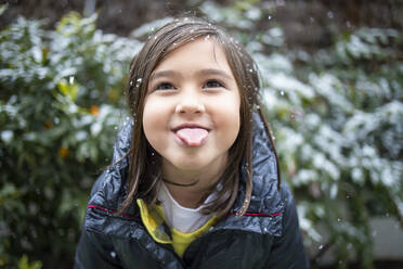 Niedliches Mädchen streckt bei Schneefall die Zunge heraus - IFRF00361