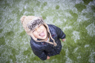 Mädchen in warmer Kleidung streckt bei Schnee die Zunge heraus - IFRF00363