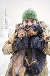 Älterer Mann umarmt Hunde beim Heben im Winter - IFRF00371