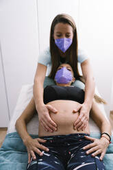Midwife examining pregnant patient while exercising - MPPF01509