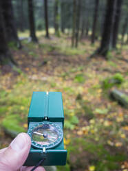 Mann hält Navigationskompass im Wald - HUSF00221