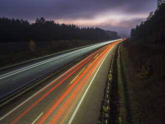 Lichtspuren auf der Autobahn gegen den Himmel in der Abenddämmerung - HUSF00222