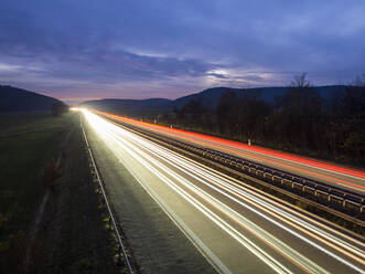 Light trails on motorway against cloudy sky - HUSF00223