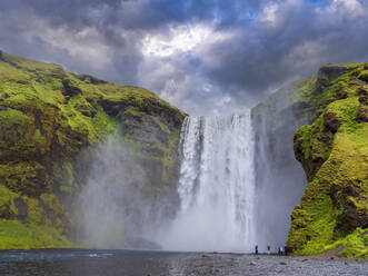 Touristen am Skogafoss-Wasserfall bei bewölktem Himmel, Island - LAF02662