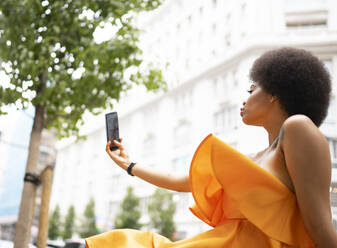 Young woman taking selfie through smart phone in city - JCCMF01145