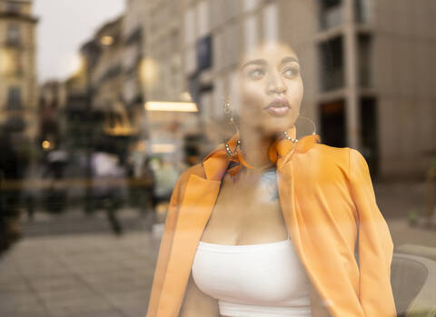 Thoughtful woman looking through glass at cafe stock photo