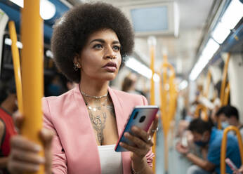 Afro woman with smart phone in train - JCCMF01176