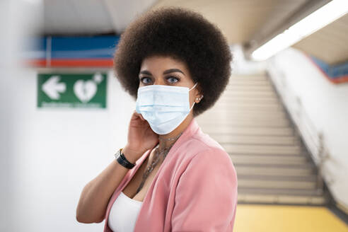 Junge Frau mit Gesichtsmaske in der U-Bahn während der Pandemie - JCCMF01180