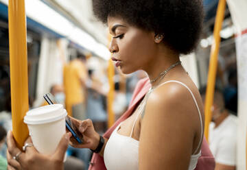 Junge Frau, die im Zug eine SMS auf ihrem Mobiltelefon schreibt - JCCMF01182