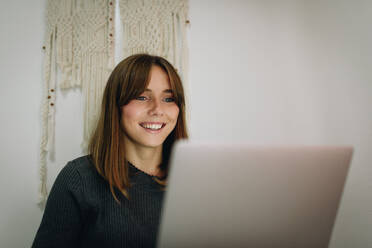 Blonde girl sitting on the bed and working with a laptop - ADSF20642