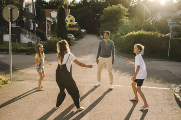 Glückliche Familie spielt mit Fußball auf der Straße - MASF21362