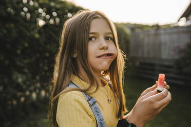 Vorpubertäres Mädchen, das beim Essen einer Wassermelone im Hinterhof wegschaut - MASF21364