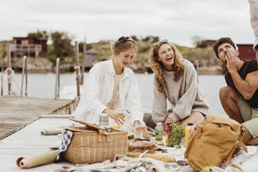 Lachende Freunde bei einem Picknick am Hafen - MASF21390