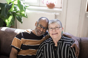 Lächelndes Paar mit Arm um sitzt auf Sofa zu Hause - MASF21419
