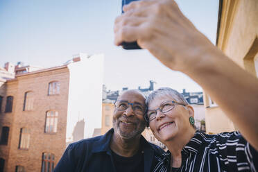 Lächelndes Paar nimmt Selfie durch Smartphone gegen Himmel in Balkon - MASF21427