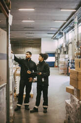 Female and male colleagues examining at distribution warehouse - MASF21441