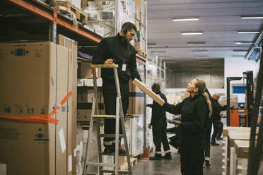 Männlicher und weiblicher Mitarbeiter halten ein Paket im Logistiklager - MASF21457