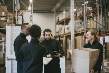 Männliche und weibliche Arbeiter diskutieren während einer Besprechung im Logistiklager - MASF21475