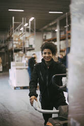 Porträt einer lächelnden Lagerarbeiterin, die Maschinen bedient - MASF21487