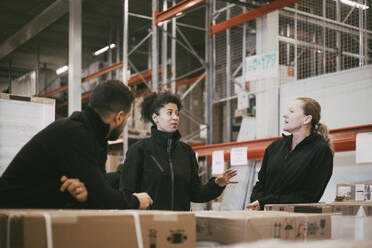 Businesswoman discussing with male and female colleagues in warehouse - MASF21496