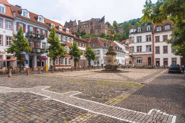 Germany, Baden-Wurttemberg, Heidelberg, Muttergottesbrunnen fountain on empty Kornmarkt square with Heidelberg Castle in background - TAMF02873