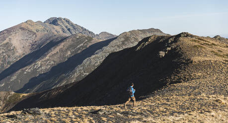 Male explorer running while trekking in mountain on sunny day - JAQF00244