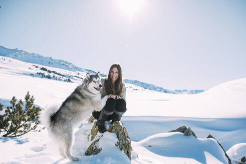 Junge Frau mit ihrem Hund im schneebedeckten Land gegen den klaren Himmel - DAMF00692